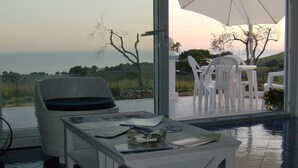 A modern outdoor seating area with a pool, white furniture, and a view of the sea. - Casamediterranea (Itri)