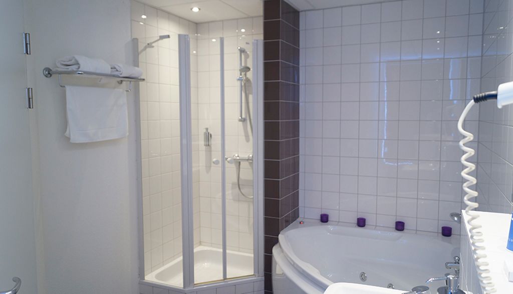 A modern bathroom with a glass-enclosed shower, a freestanding bathtub, and a white sink.