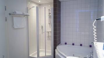 A modern bathroom with a glass-enclosed shower, a freestanding bathtub, and a white sink.