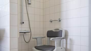 Een douchegedeelte met een handdouche, een doucheaanslag en een witte plastic stoel.