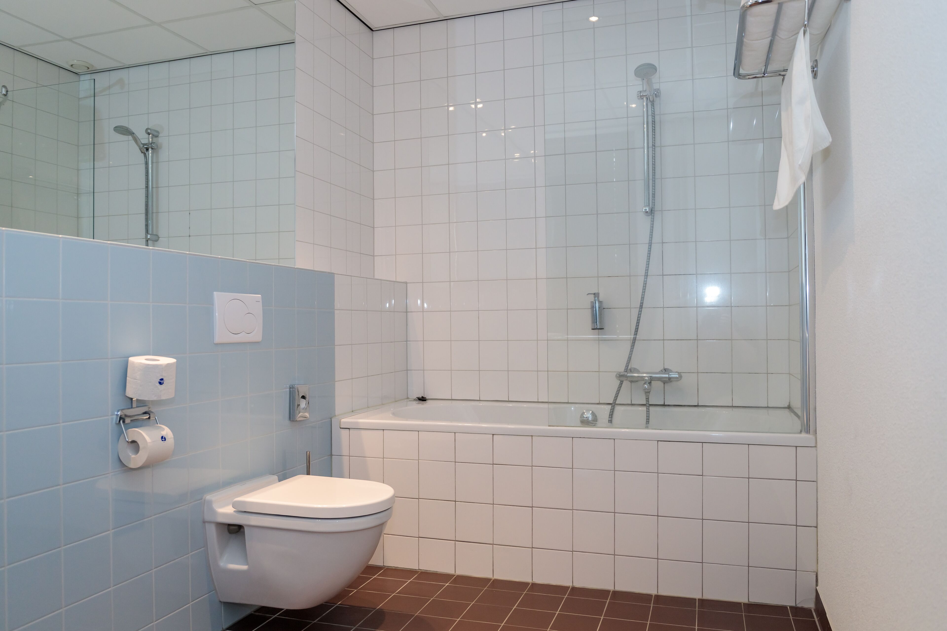 A modern bathroom with a toilet, a glass-enclosed shower, and a bathtub.