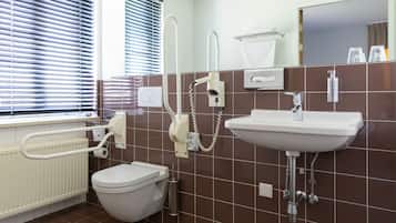 A bathroom with a toilet, sink, and shower. There are towels and toiletries on the wall.