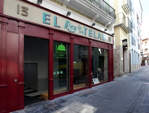 Um edifício com fachada vermelha e uma placa que diz 'EL Rey de las TELAS'.