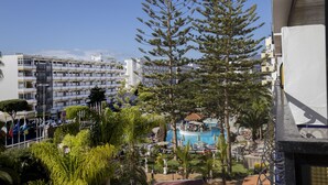 Un hotel con piscina, rodeado de exuberante vegetación y vistas a un paisaje urbano.