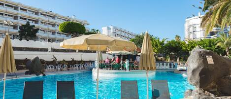 Un espace piscine équipé de chaises longues, de parasols et d’un bar.