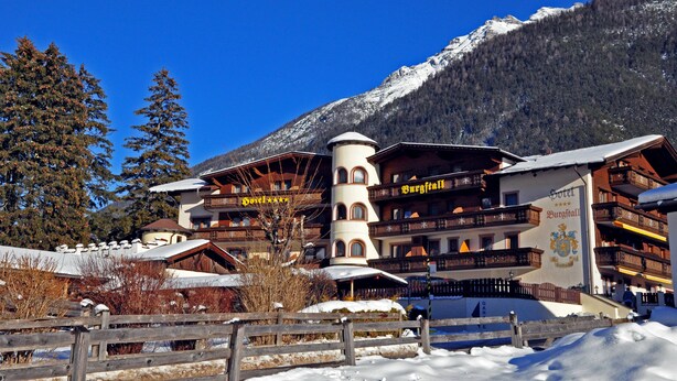 A hotel with multiple balconies, a central tower, and a mountain backdrop. - Hotel Burgstall (Neustift Im Stubaital)