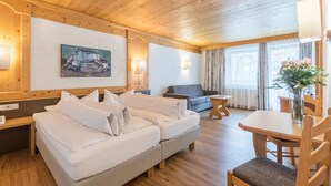 A modern hotel room with a wooden ceiling, a large bed, a sofa, a dining table, and a painting on the wall. - Hotel Burgstall (Neustift Im Stubaital)