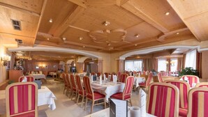 A spacious dining area with high wooden ceilings and red-striped chairs. Tables are set with white tablecloths and silverware. - Hotel Burgstall (Neustift Im Stubaital)