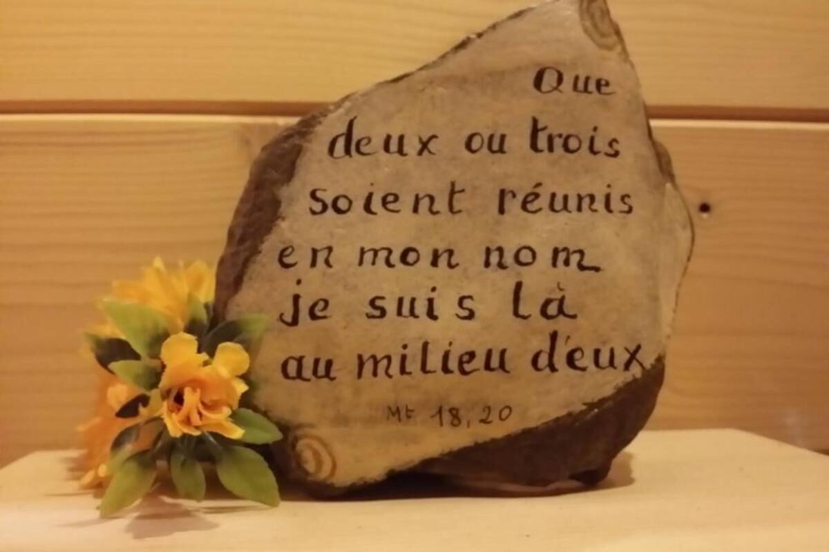 A stone with French text and a small yellow flower.
