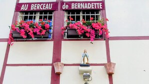 Un bâtiment sur lequel on peut lire l’inscription « Au Berceau de Bernadette », et sur lequel est érigée une statue de Bernadette.