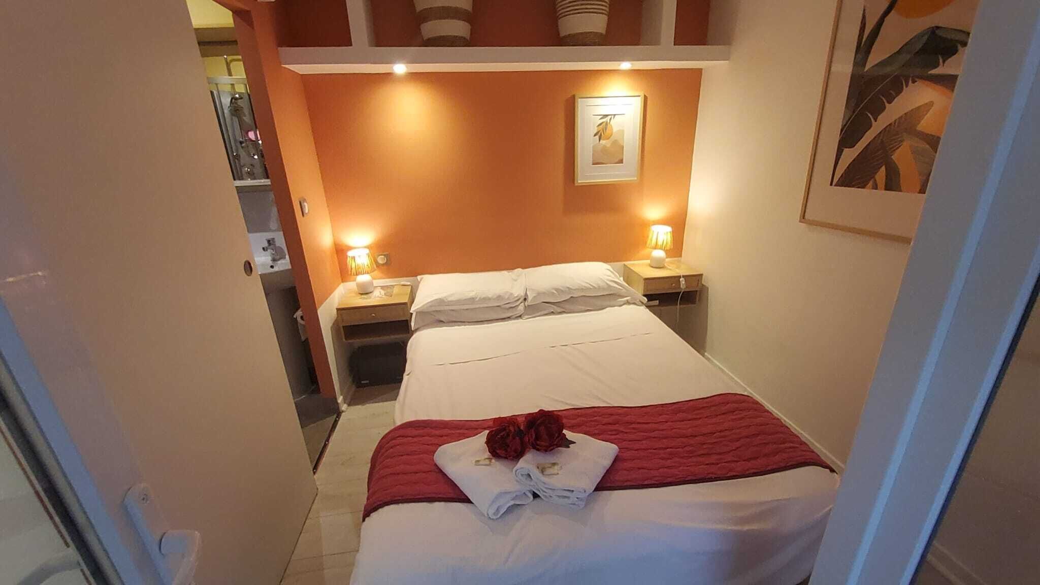 Een hotelkamer met een bed, twee bedlampen, een nachtkastje en een lijst aan de muur.