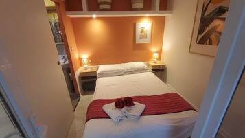 Een hotelkamer met een bed, twee bedlampen, een nachtkastje en een lijst aan de muur.