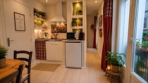 A compact kitchen with a refrigerator, microwave, and a dining area with a table and chairs.