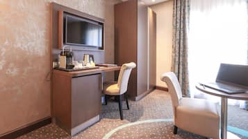 Una habitación de hotel con escritorio, silla, laptop, televisor y cama.