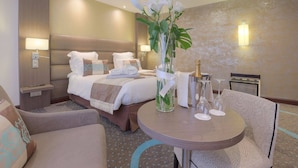A hotel room with a bed, bedside tables, a desk, and a chair.