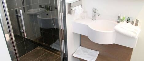 A modern bathroom with a glass shower enclosure, a white sink, and a wooden vanity.