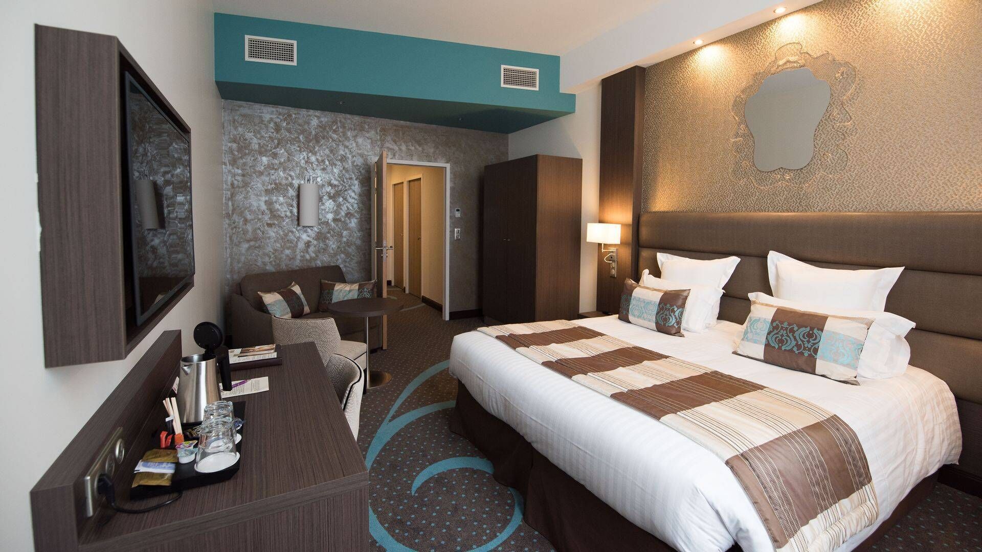 Habitación de hotel con una cama grande, un escritorio con silla, televisor y baño con ducha e inodoro.