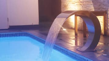 A modern indoor pool with a water feature.