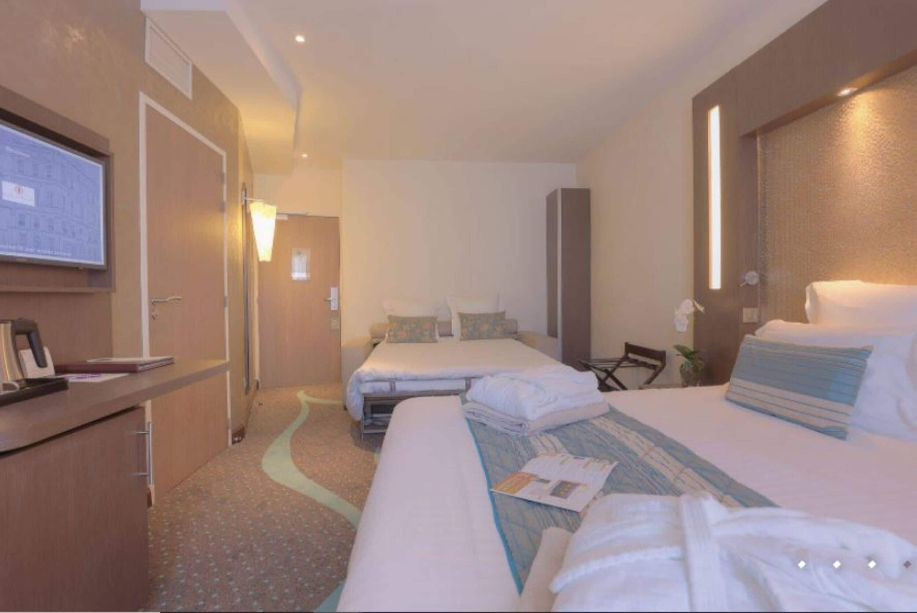 Une chambre d’hôtel avec un grand lit, un bureau avec une chaise, une petite table et un miroir.