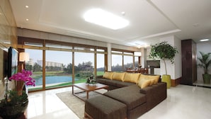 Ein geräumiges Wohnzimmer mit einer großen Eckcouch, einem Couchtisch und Blick auf einen Golfplatz durch große Fenster.