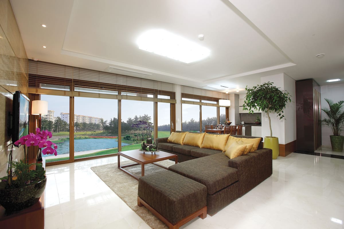 A spacious living room with a large sectional sofa, a coffee table, and a view of a golf course through large windows.