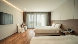 Ein Hotelzimmer mit zwei Betten, einem Fernseher, einem Schreibtisch und einem Stuhl.