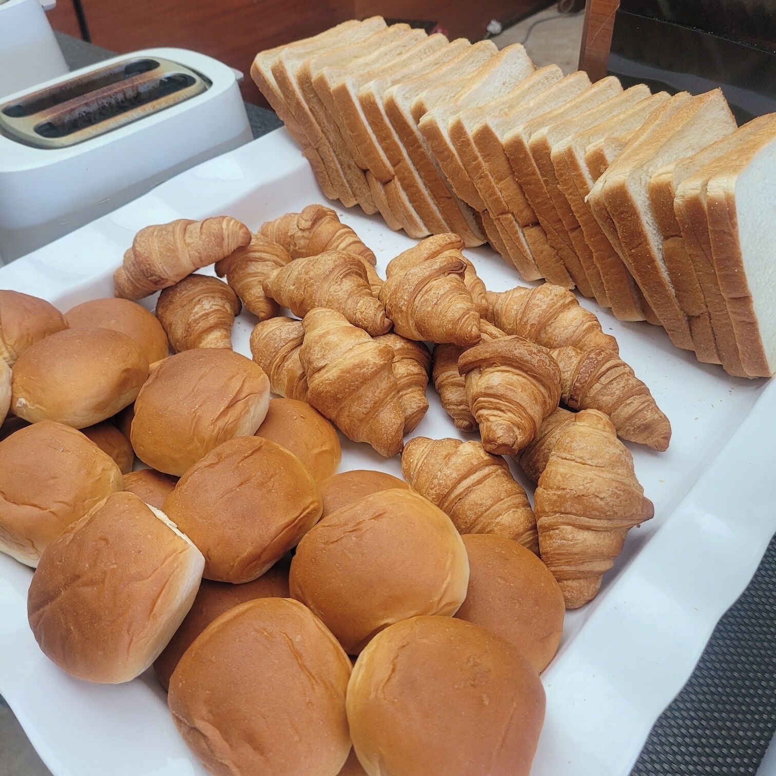 Un plateau contenant un assortiment de produits de boulangerie, notamment du pain, des petits pains et des croissants.