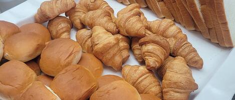 Un plateau contenant un assortiment de produits de boulangerie, notamment du pain, des petits pains et des croissants.