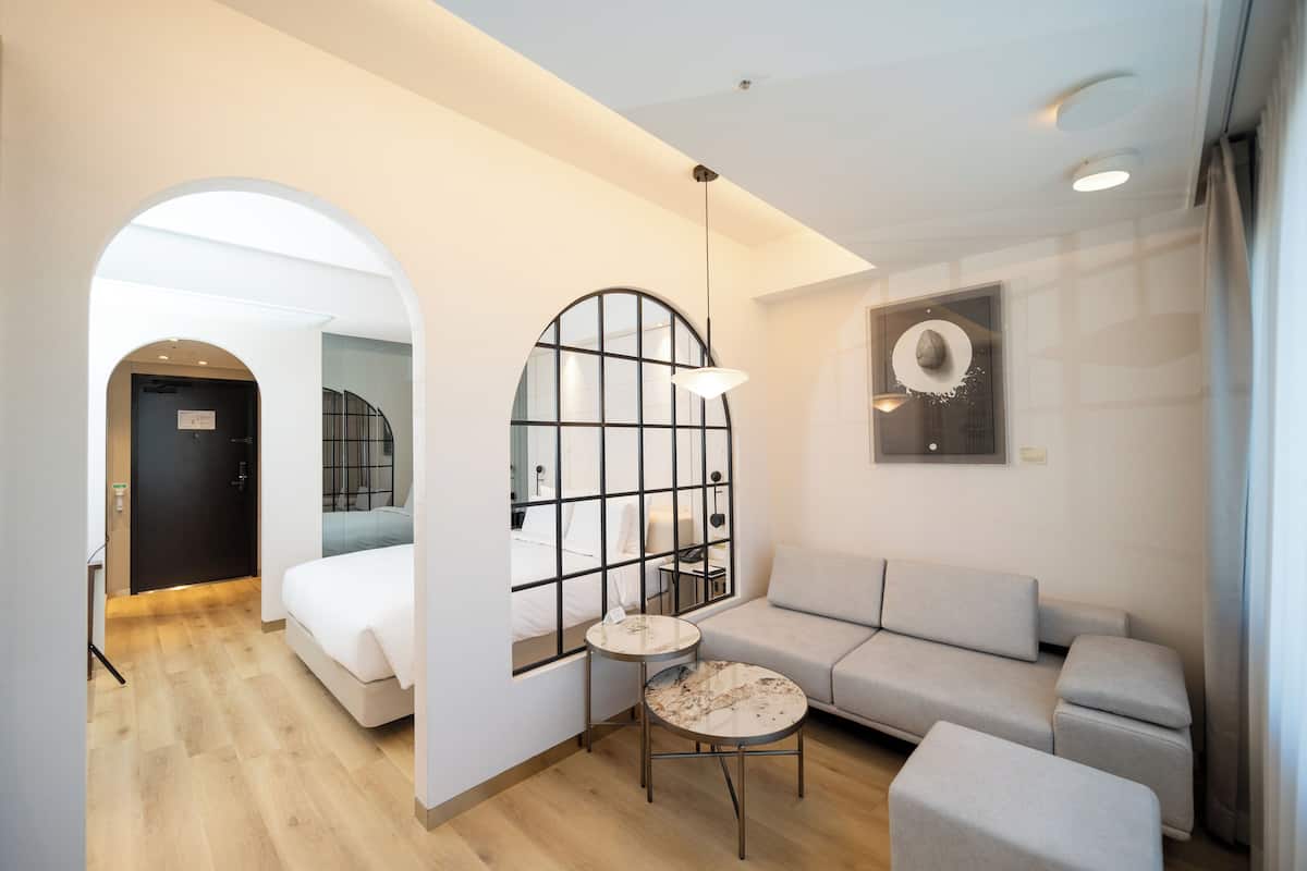 Una habitación de hotel moderna con sofá, una mesita redonda y una cama.