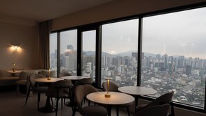 Habitación de hotel moderna con ventanas grandes que ofrecen vistas a la ciudad.