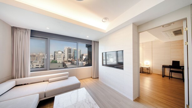 Una sala de estar moderna con un gran ventanal, un sofá, una mesa de centro y un televisor.