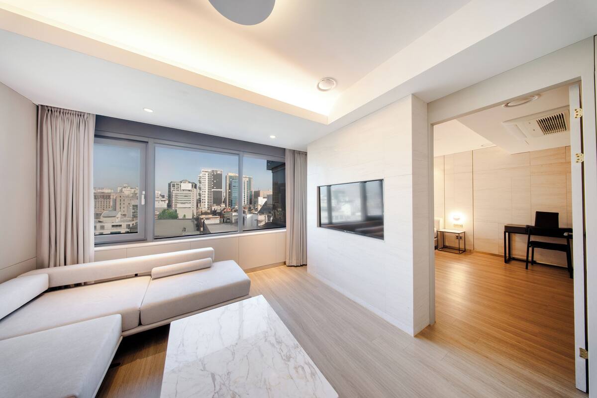 Una sala de estar moderna con un gran ventanal, un sofá, una mesa de centro y un televisor.