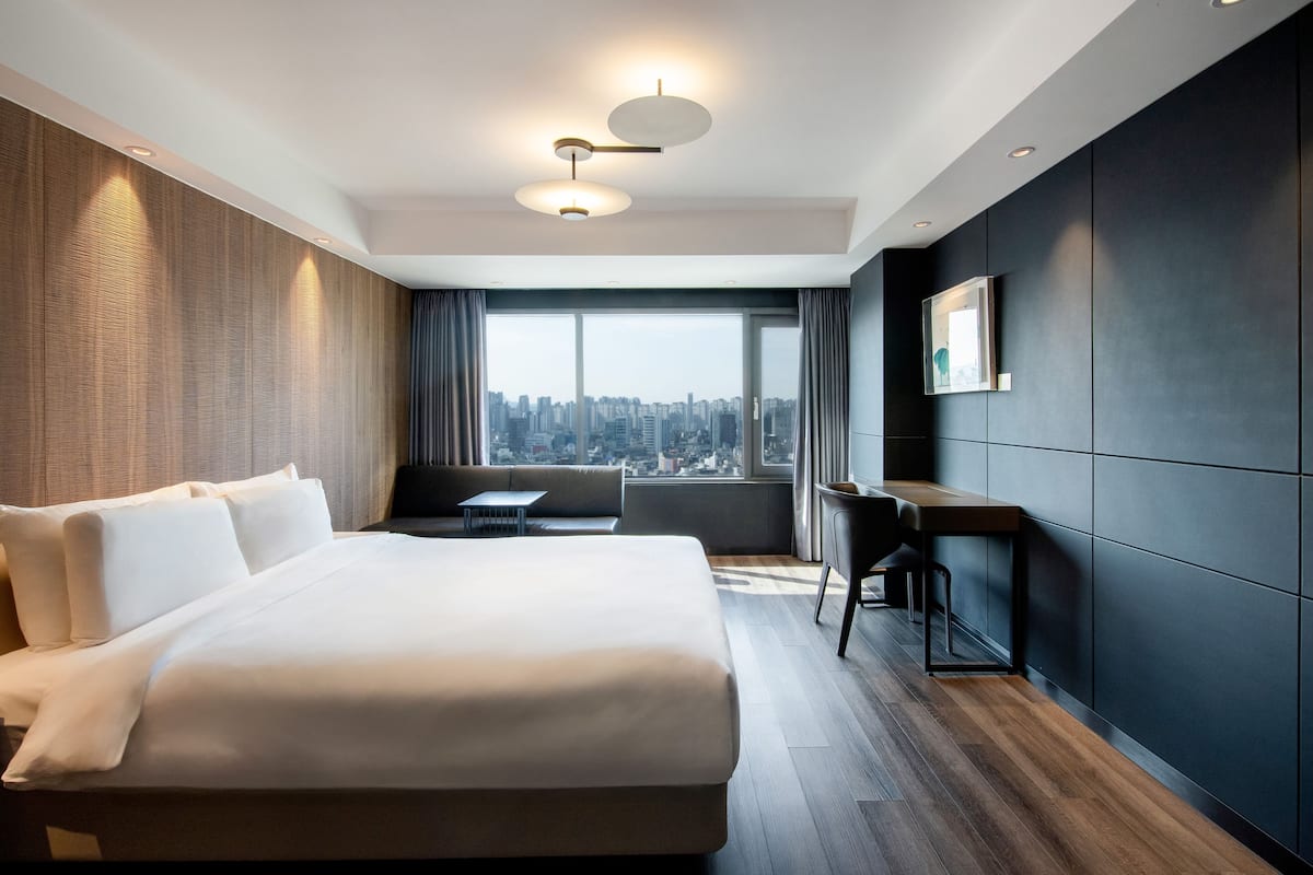 Una habitación de hotel moderna con una cama grande, un escritorio y vistas a la ciudad.
