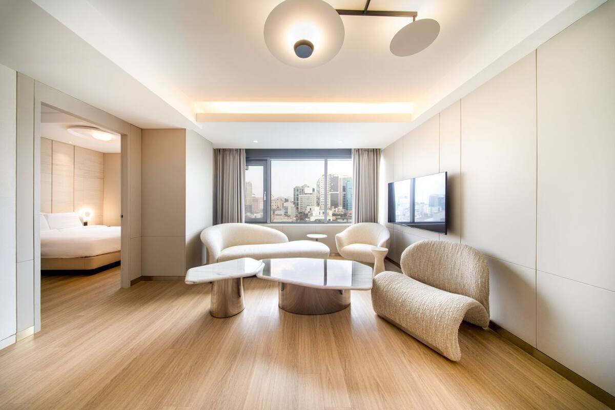 Una habitación de hotel moderna con vistas a la ciudad, una cama, un área de descanso con una mesita de café y un televisor de pantalla plana.