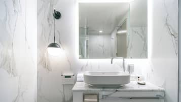 A modern bathroom with a large marble sink, a mirror, and a built-in heater.