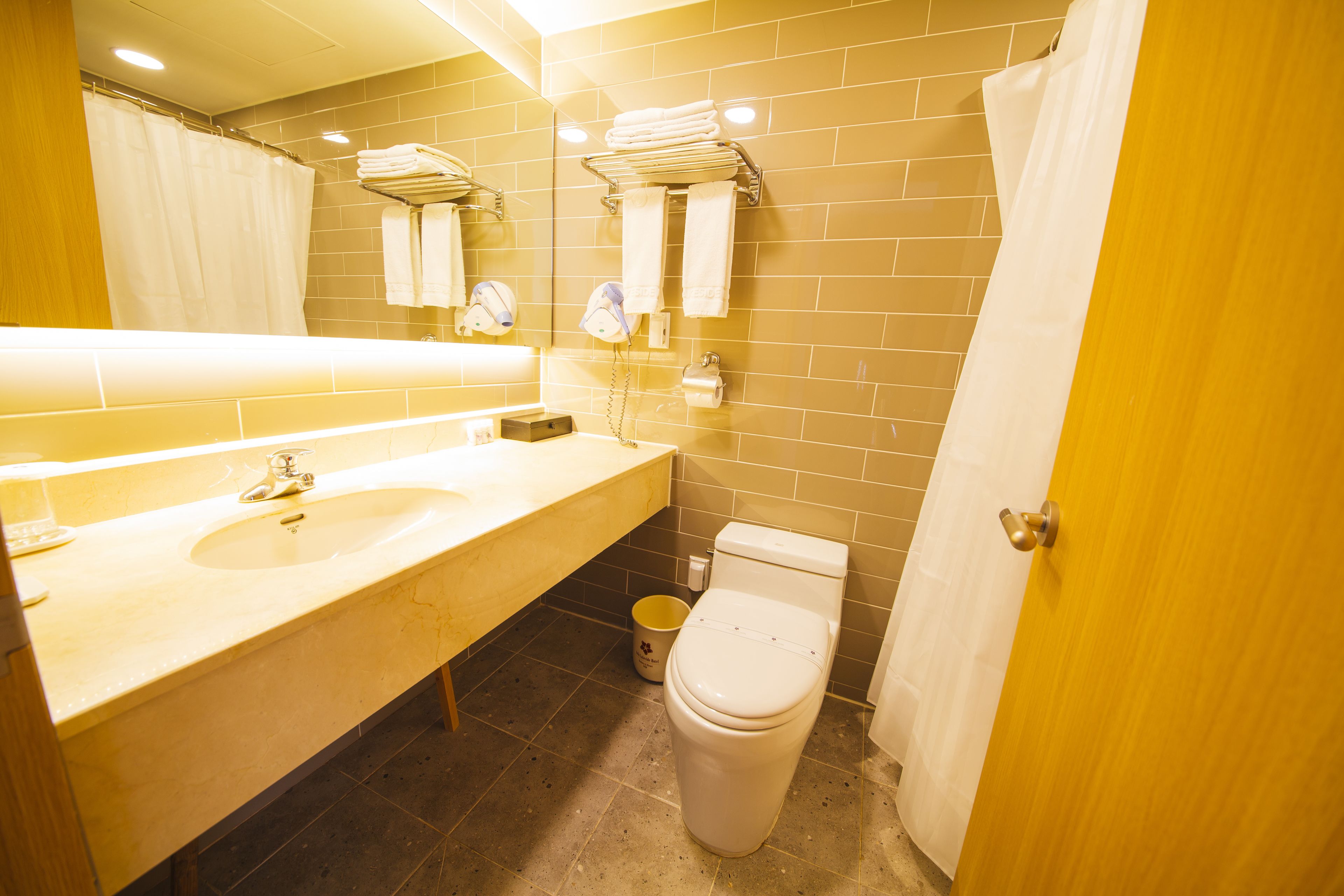 Un baño con lavamanos, inodoro y cortina de ducha.