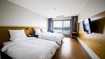 A hotel room with two beds, a TV, a desk, and a window with a view.