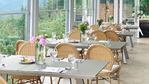 A restaurant with large windows offering a view of mountains and greenery. Tables are set with chairs and centerpieces. - Asia Lakeside Hotel (Jinju)