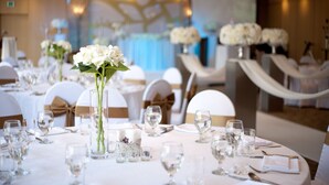 A formal dining room with round tables set for a meal, each with a centerpiece of white flowers and clear glassware. - Asia Lakeside Hotel (Jinju)