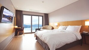 A hotel room with a large bed, a desk, a chair, a TV mounted on the wall, and a view of the outdoors. - Asia Lakeside Hotel (Jinju)