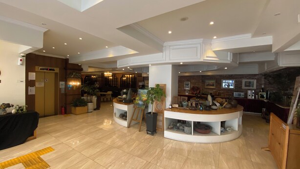 A spacious lobby with a reception desk, seating area, and a dining section.