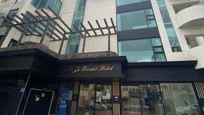 A modern hotel with a prominent entrance, large windows, and a clear sky.