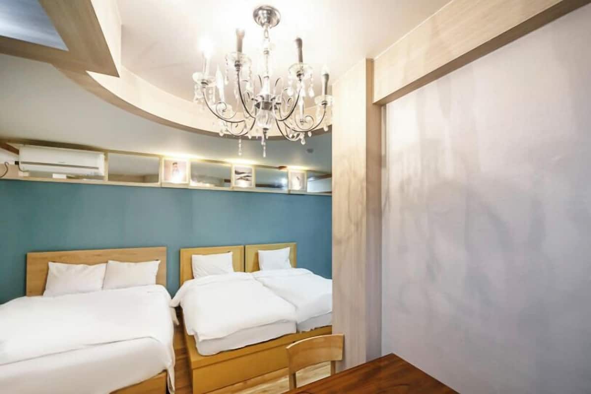 A hotel room with two beds, a chandelier, and a wooden ceiling.