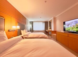 A hotel room with two beds, a desk, a television, and a view of a mountainous landscape.