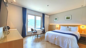 Een hotelkamer met een bed, een bureau, een stoel en uitzicht op het buitenland.