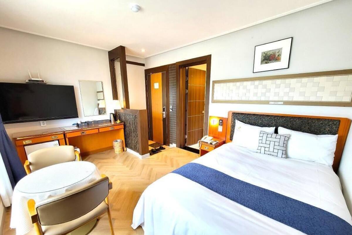 A hotel room with a bed, a desk, a television, and a chair.