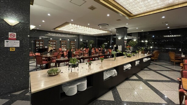 Eine Hotlellobby mit einer langen Rezeption, mehreren Sitzbereichen und einem Chandelier.