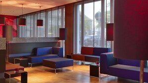 Un espacio lounge moderno con sofás y mesas, ventanas amplias e iluminación colgante.