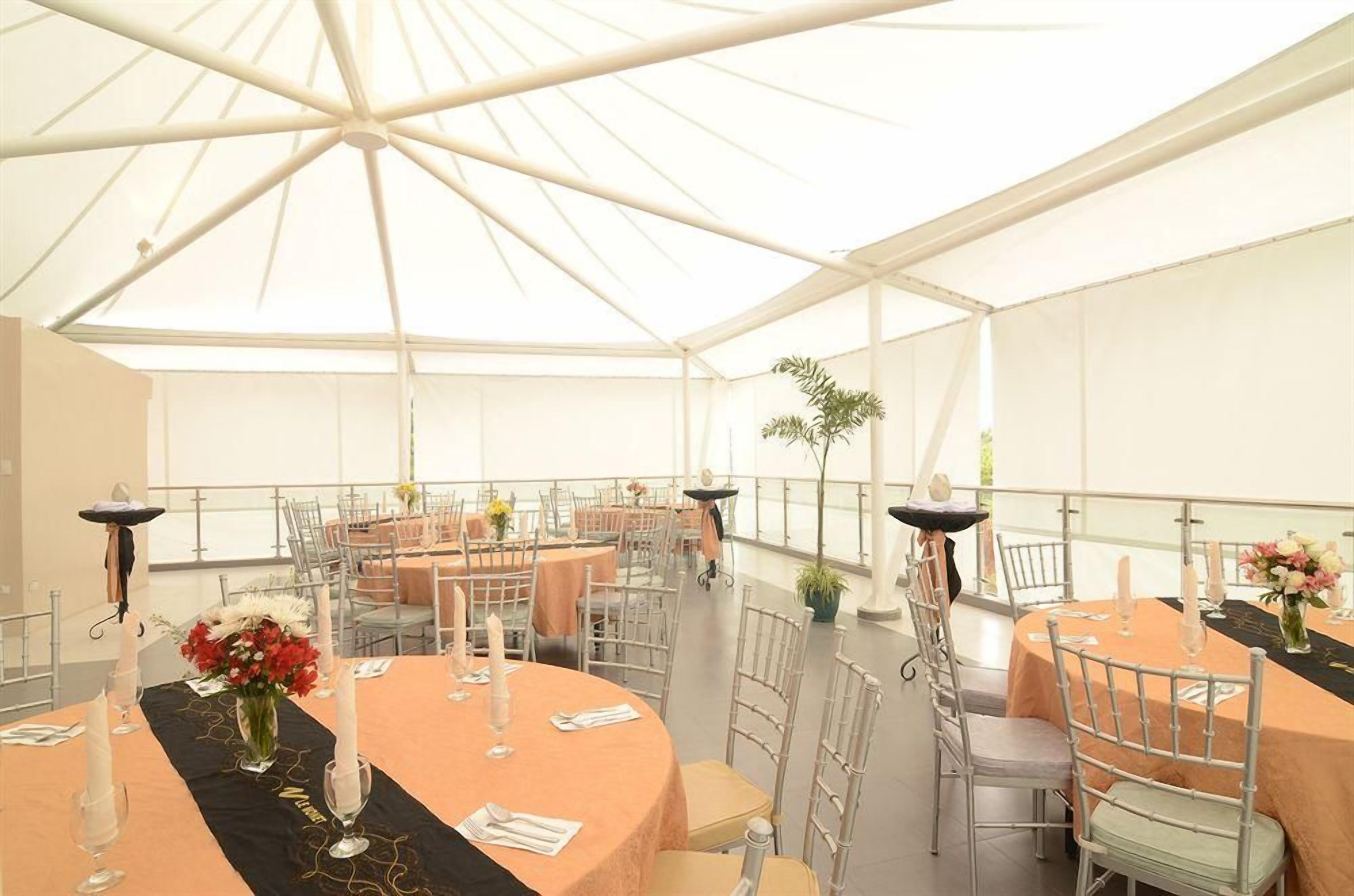 A covered outdoor dining area with round tables, chairs, and candles.