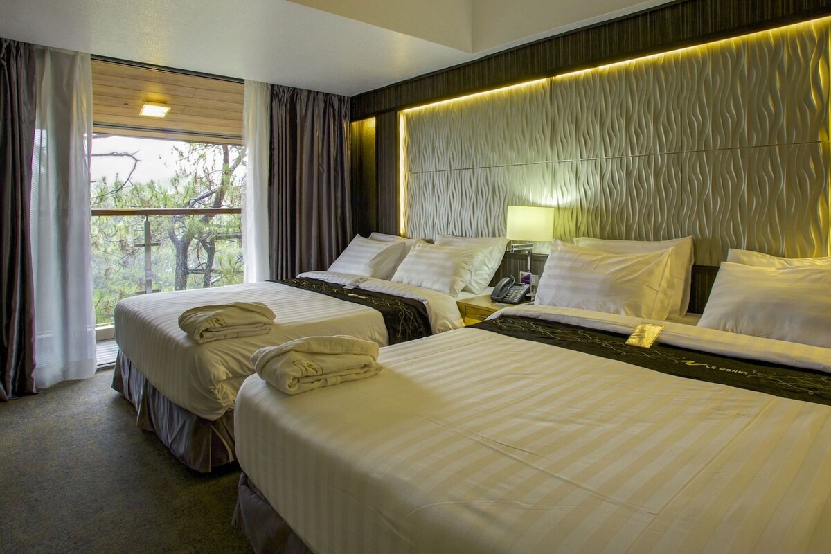 A hotel room with two beds, a large window with curtains, and a wall with a textured pattern.